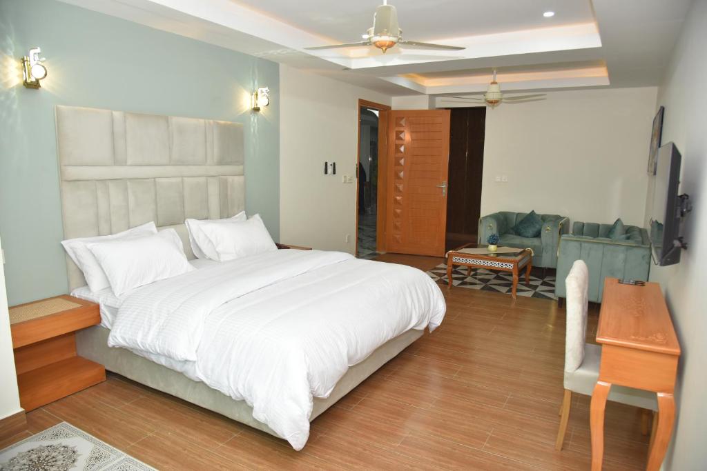 a bedroom with a large white bed and a desk at Scenic Hotel Near Earthquake Memorial Bridge,203 in Muzaffarabad