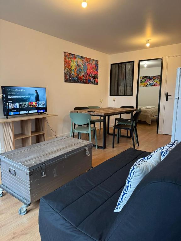 a living room with a table and a tv at Logement 11 parking gratuit in Poitiers