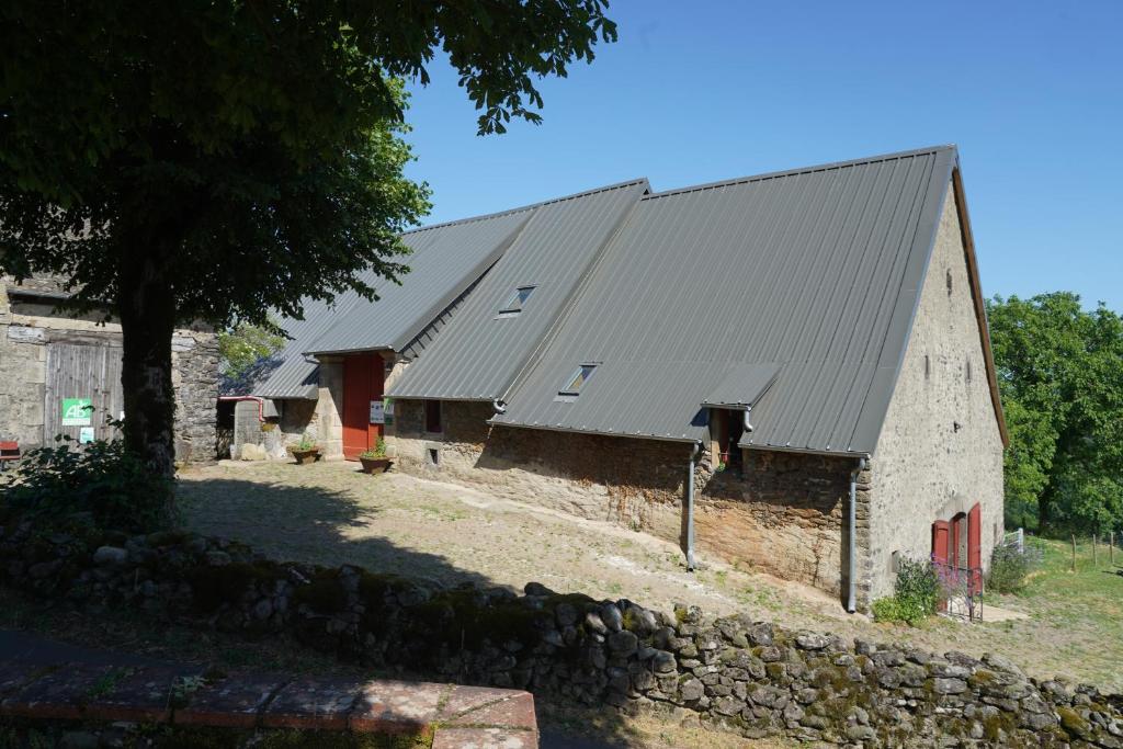 a large stone barn with a metal roof at Plantes et sabots in Barriac-les-Bosquets