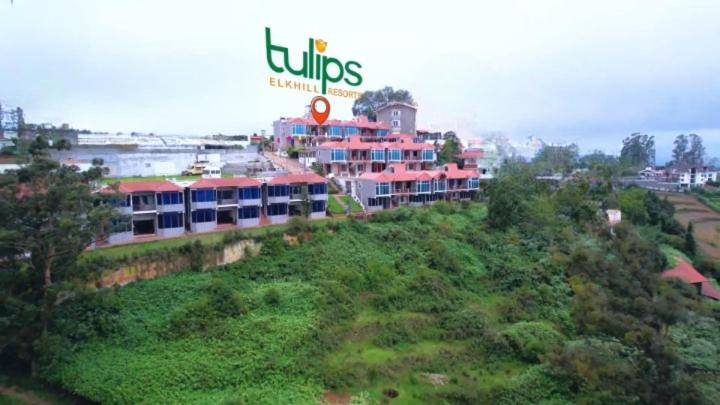 a building with a sign on top of a hill at Tulips Resorts - Elkhill in Ooty