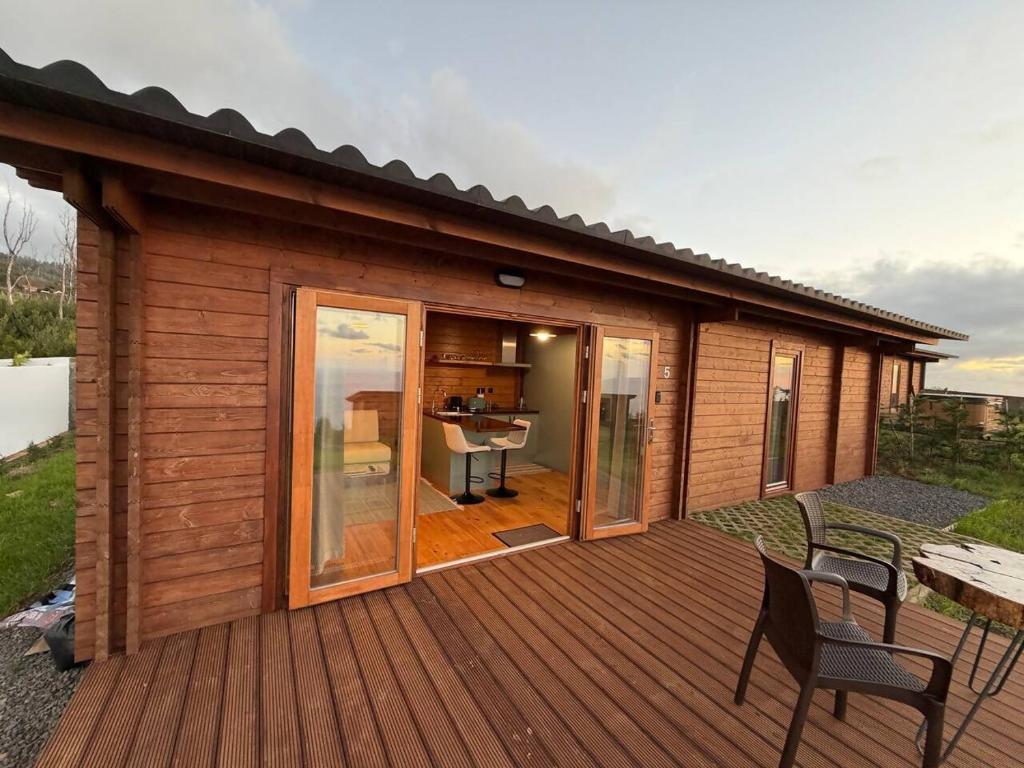 a wooden cabin with a deck with a table and chairs at Sunset Eco Shelter 5 in Ponta do Pargo