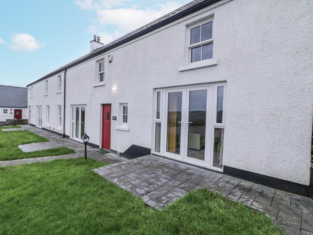 a white house with a red door and a yard at Foyle Cottage in Strabane