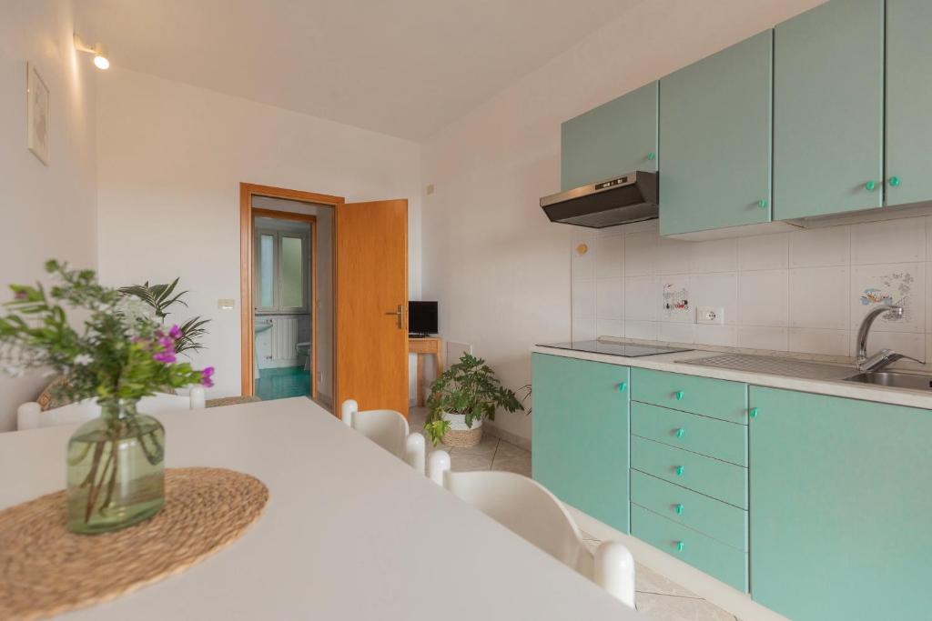 a kitchen with blue cabinets and a table with a vase of flowers at Appartamenti Belvedere by ElbaSummer in Lacona