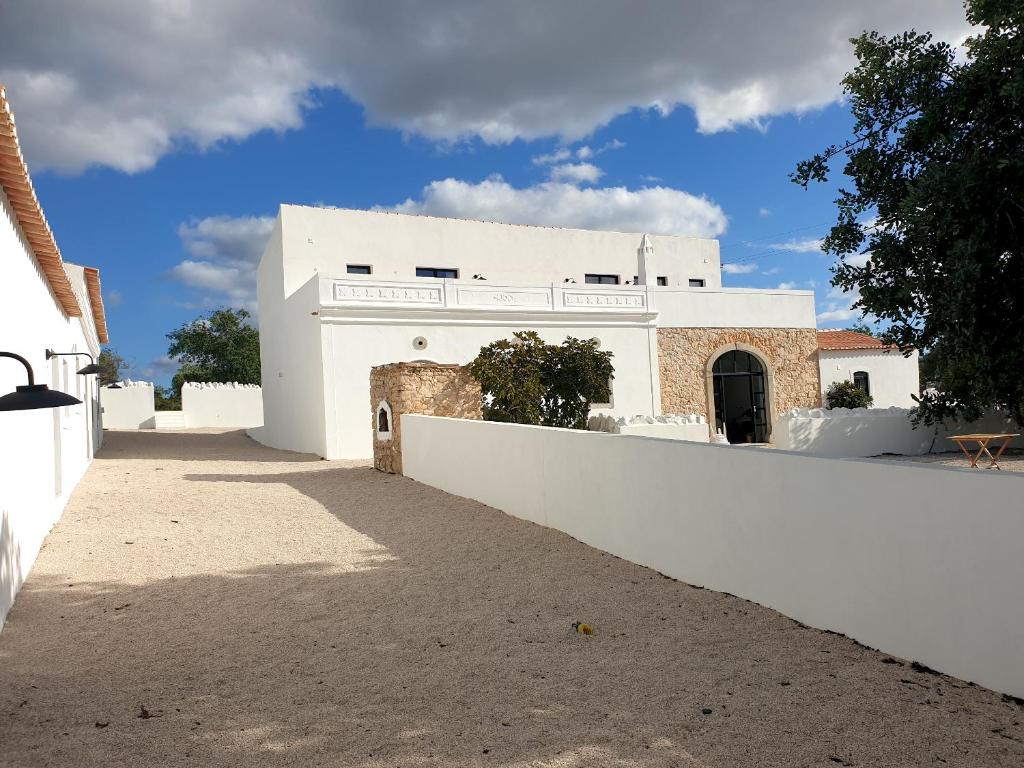 a white building with a white wall and a tree at Uma Casa Rural in Santa Bárbara de Nexe