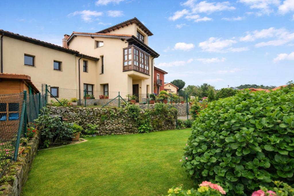 a garden with a house and a fence at Poo de Llanes Casa cerca de la Playa – El Balandro in Llanes