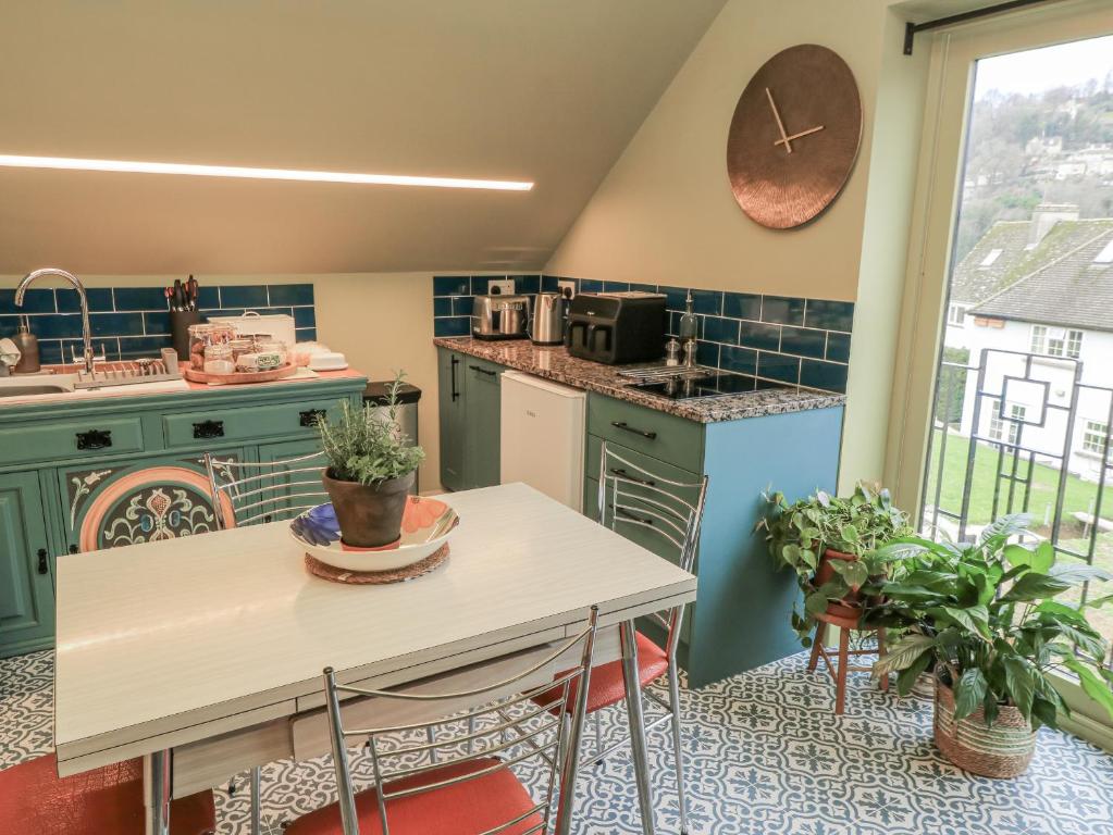 a kitchen with green cabinets and a table with plants at Golden Valley View in Stroud