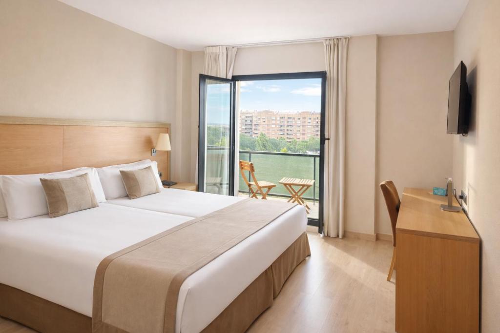 a hotel room with a large bed and a balcony at Hotel Real in Lleida