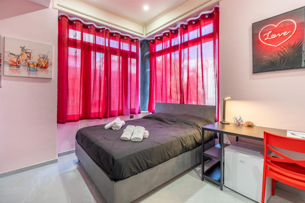 a bedroom with red curtains and a bed and a desk at Seashell Luxury Rooms Sanremo in Sanremo
