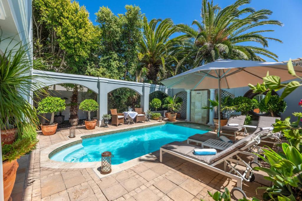 a swimming pool with a patio and an umbrella at Maison du Cap in Cape Town