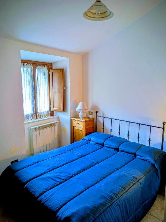 a bedroom with a blue bed and a window at Lucoli Antico in Vado Lucoli