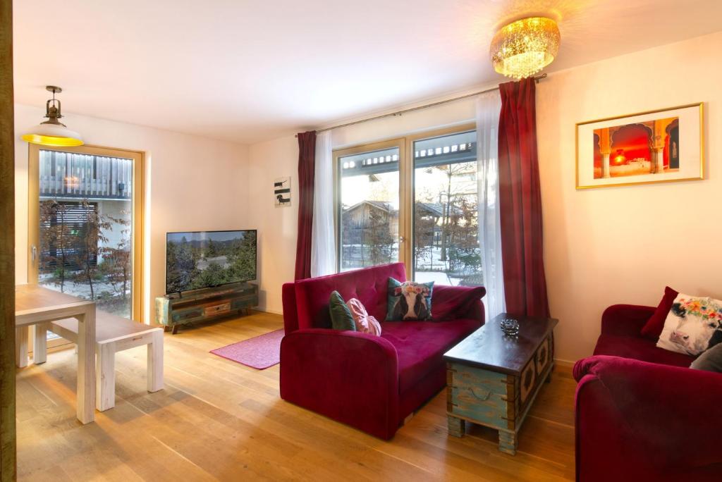 a living room with two red chairs and a tv at Karwendelperle -419- in Mittenwald