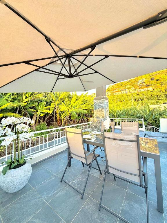 a table and chairs under an umbrella on a patio at Refúgio do Vale Verde in Ponta do Sol