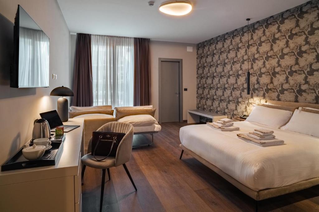 a hotel room with two beds and a desk at Porpora Suite Hotel in Milan
