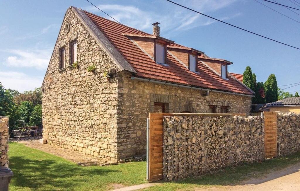 a stone building with a red roof and a fence at Modern stone house in Balatonfüred with jacuzzi in Balatonfüred