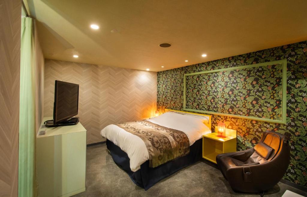 a bedroom with a bed and a tv and a chair at Hotel Flower Style koriyama tenri in Tenri