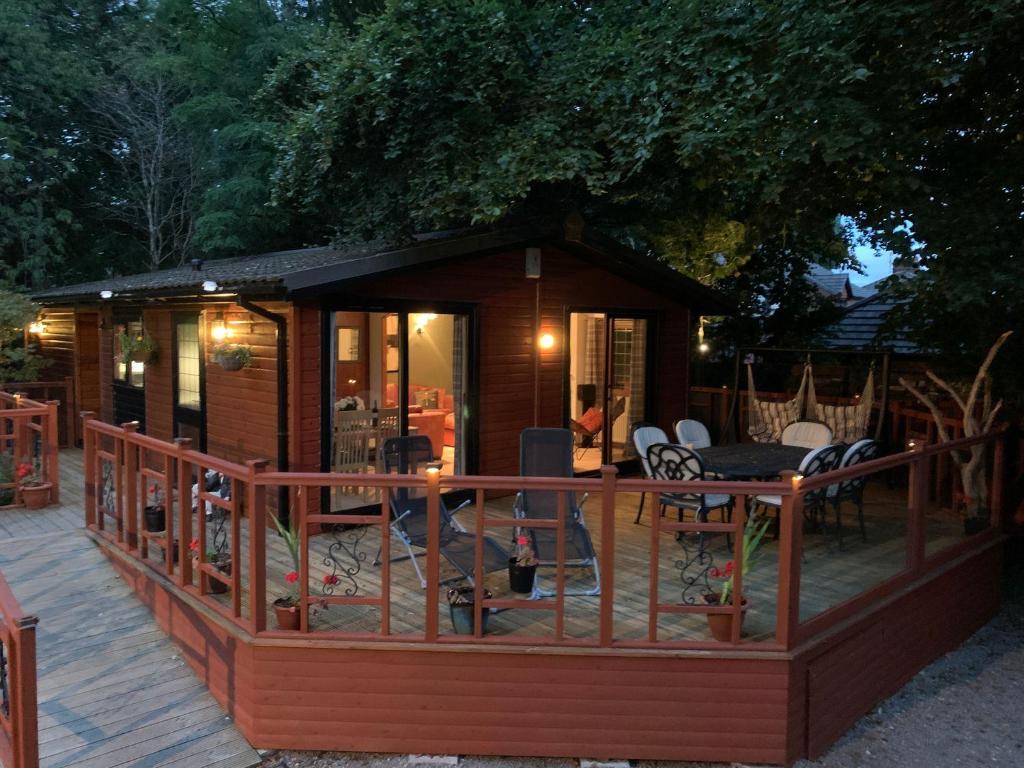 a large wooden cabin with a deck with chairs at The Hermitage in Penrith