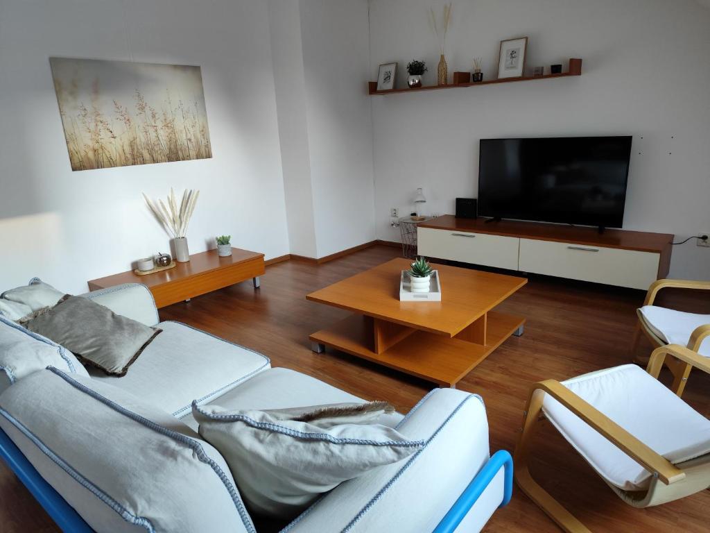a living room with white furniture and a flat screen tv at Rooftop Apartment in Šamorín
