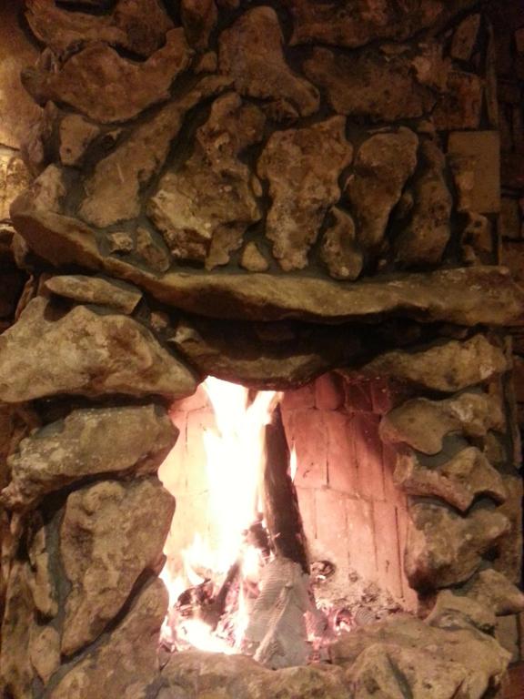 a stone fireplace with a fire in it at Uysallar Koy Evi in Gokceada Town