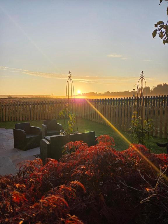 a sunset over a garden with couches and flowers at The Cairn at North Lodge, Rural Guest Suite in Kirriemuir