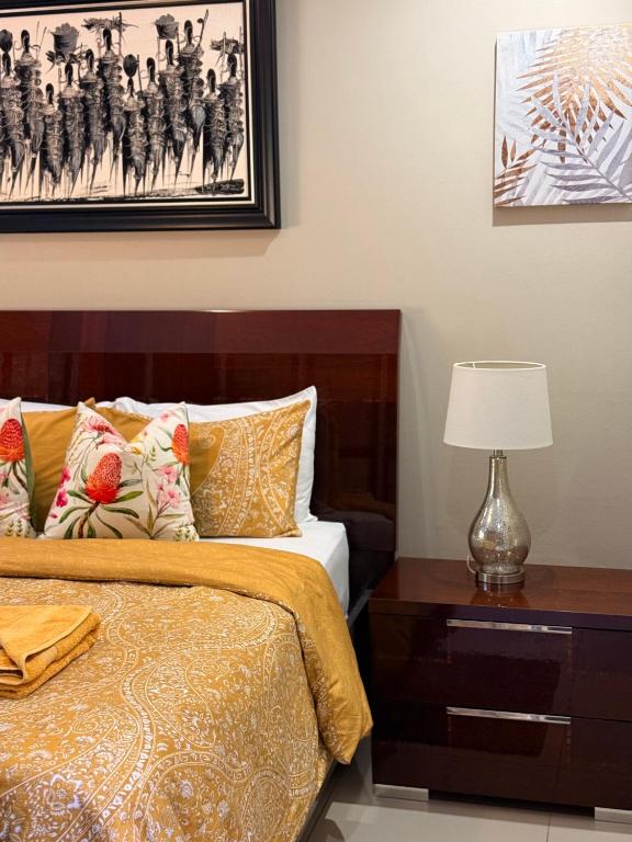 a bedroom with a bed and a table with a lamp at Amira Boutique Villa in Empangeni