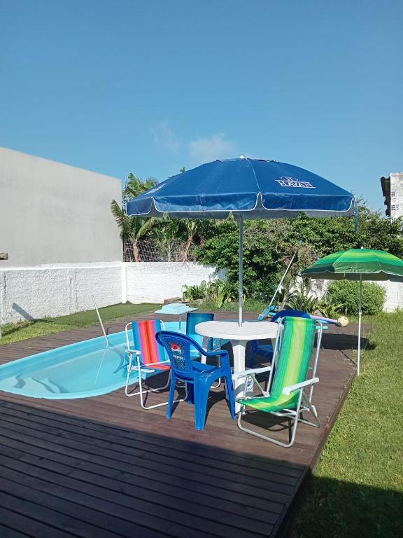 a table with chairs and an umbrella next to a pool at QUARTO AZUL com cozinha e piscina só sua in Capão da Canoa