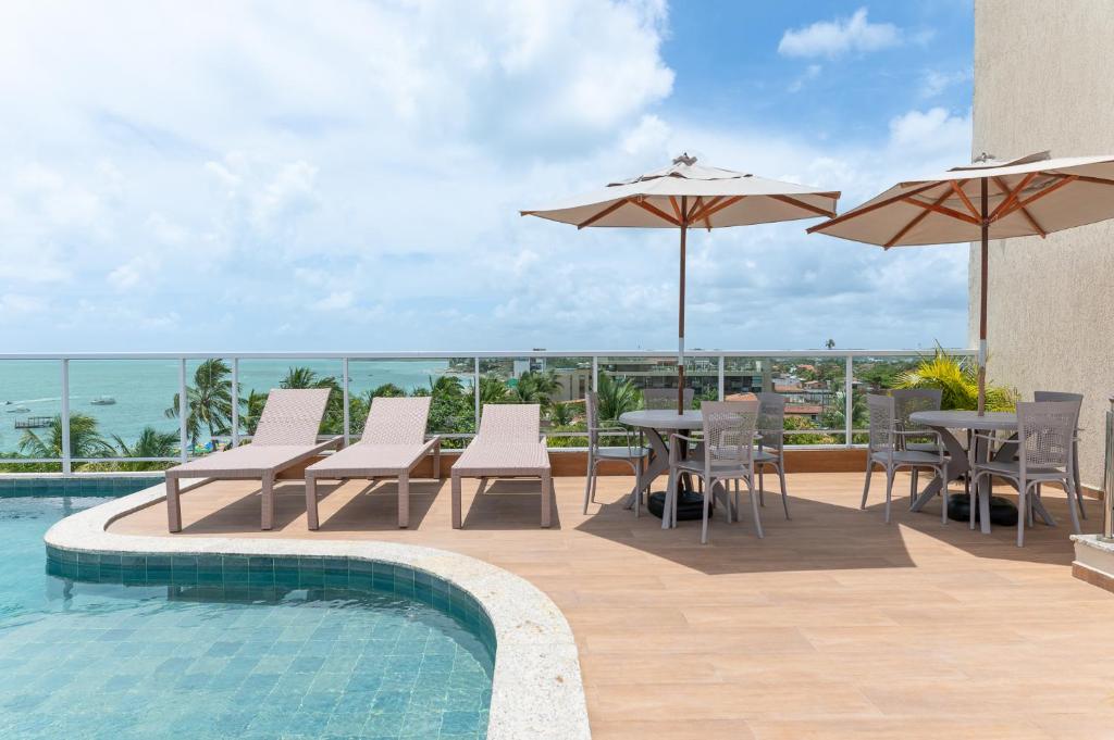 a pool with chairs and tables and umbrellas at Flat Coqueiros 101 Praia in Tamandaré