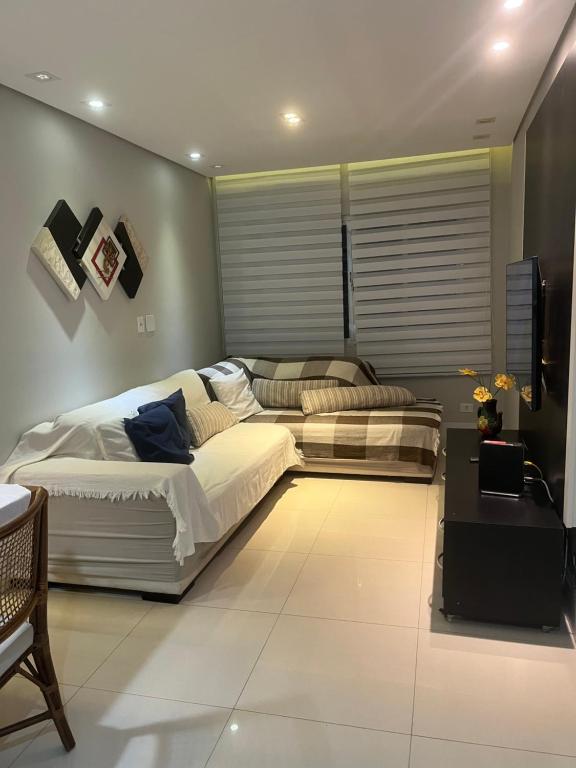 a bedroom with two beds and a tv in it at Apartamento Zapata Guarujá in Guarujá