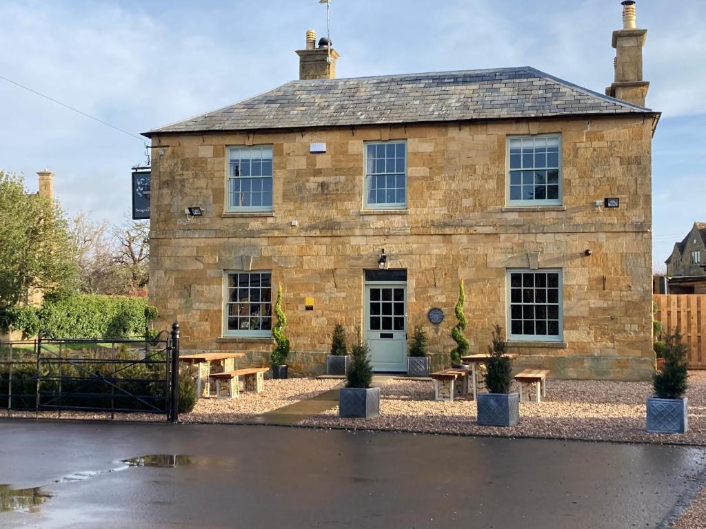 a stone building with picnic tables in front of it at The Seagrave Arms in Weston Subedge