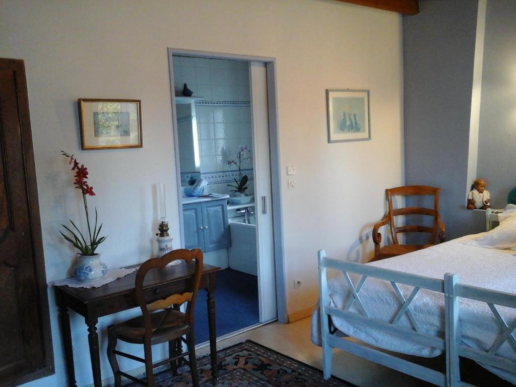 a bedroom with a bed and a table and a kitchen at LES Roses Trémières in Gémozac