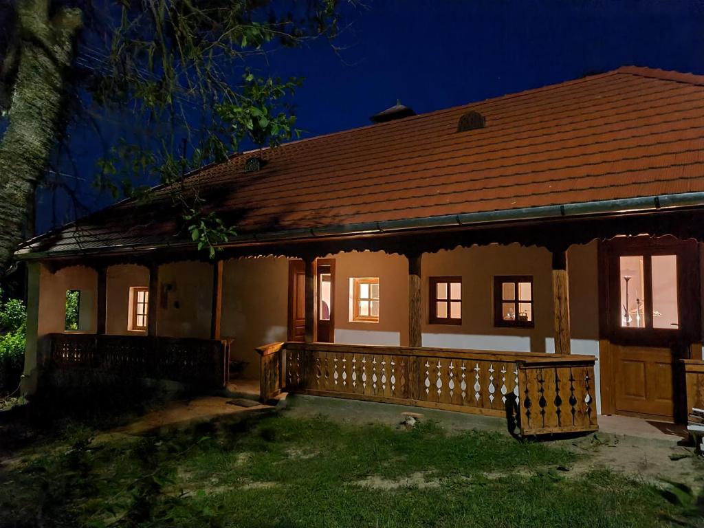 a small house with a wooden porch at night at Füstös Cottage Gömörszőlős in Gömörszőlős