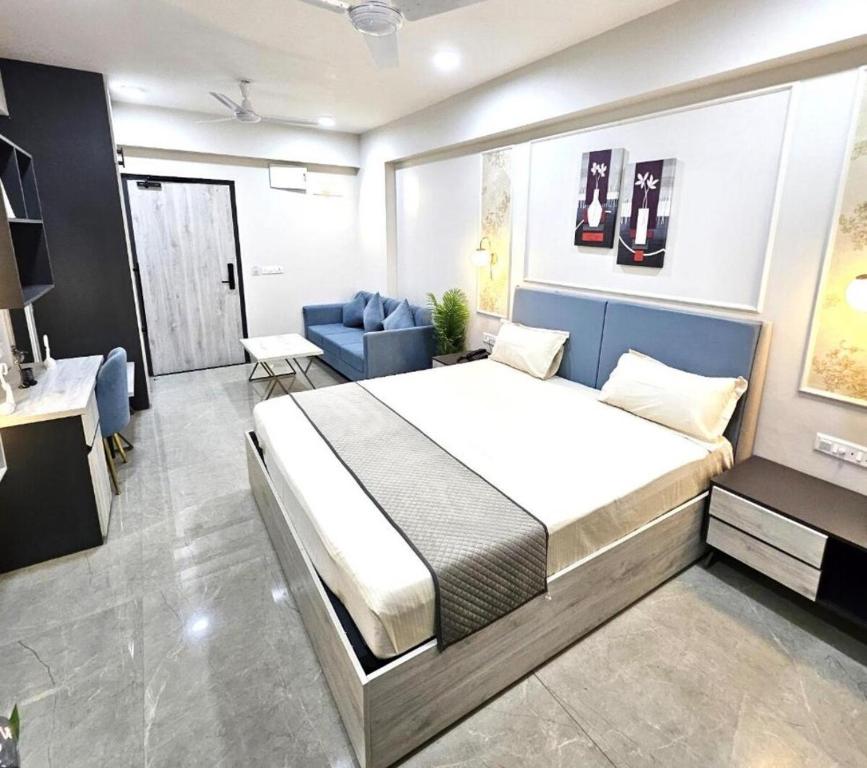 a bedroom with a large bed and a blue couch at Iconic Studio Apartment in Jaipur in Jaipur