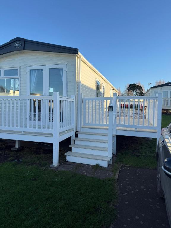 a mobile home with a white deck and stairs at Coastal Caravan Seton Sands in Port Seton