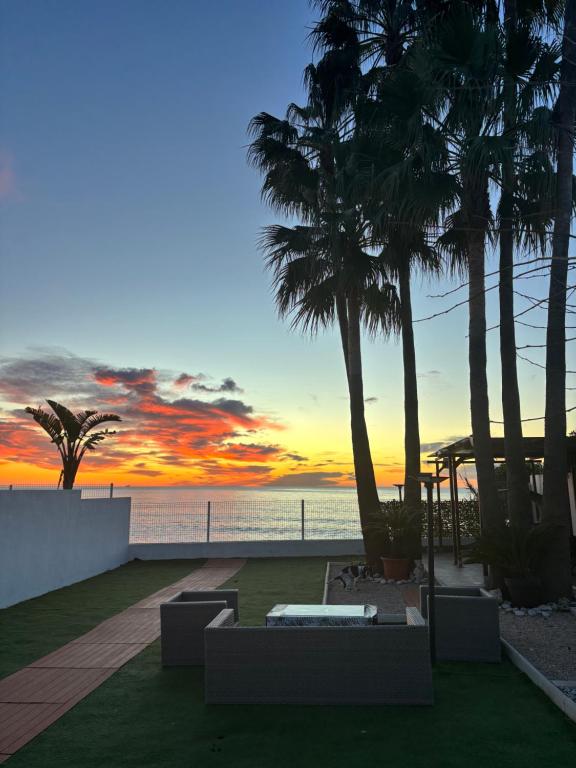 a sunset over the ocean with palm trees and couches at CHALET directo al MAR in Benicarló