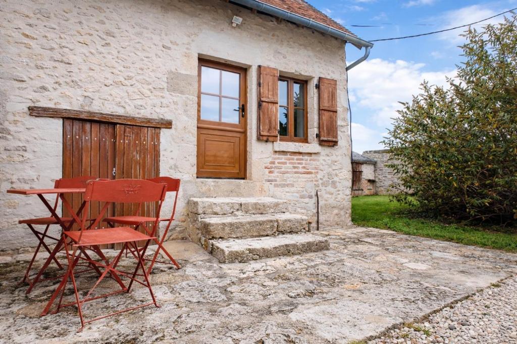 a red chair sitting in front of a house at Gîte du Noyer in Villexanton