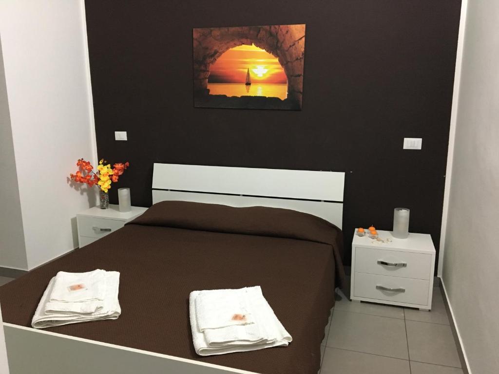 1 dormitorio con 1 cama marrón y 2 mesitas de noche en I Tre Colori della Sicilia, en Santo Stefano di Camastra