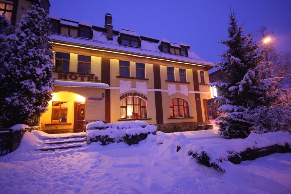 un hotel está cubierto de nieve por la noche en Hotel Karkonosze, en Kamienna Góra
