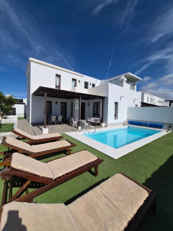 a villa with a swimming pool and a house at Casa Sunny in Yaiza