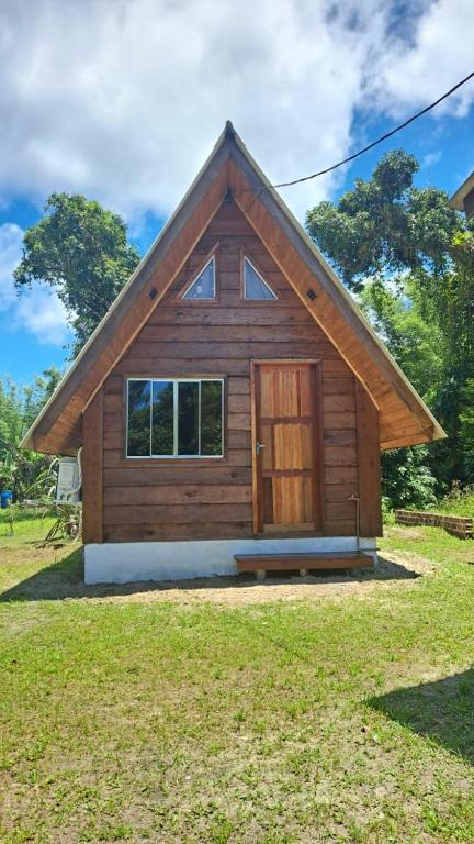 a small log cabin with a door in a yard at Chalé da Ilha in Guaraqueçaba