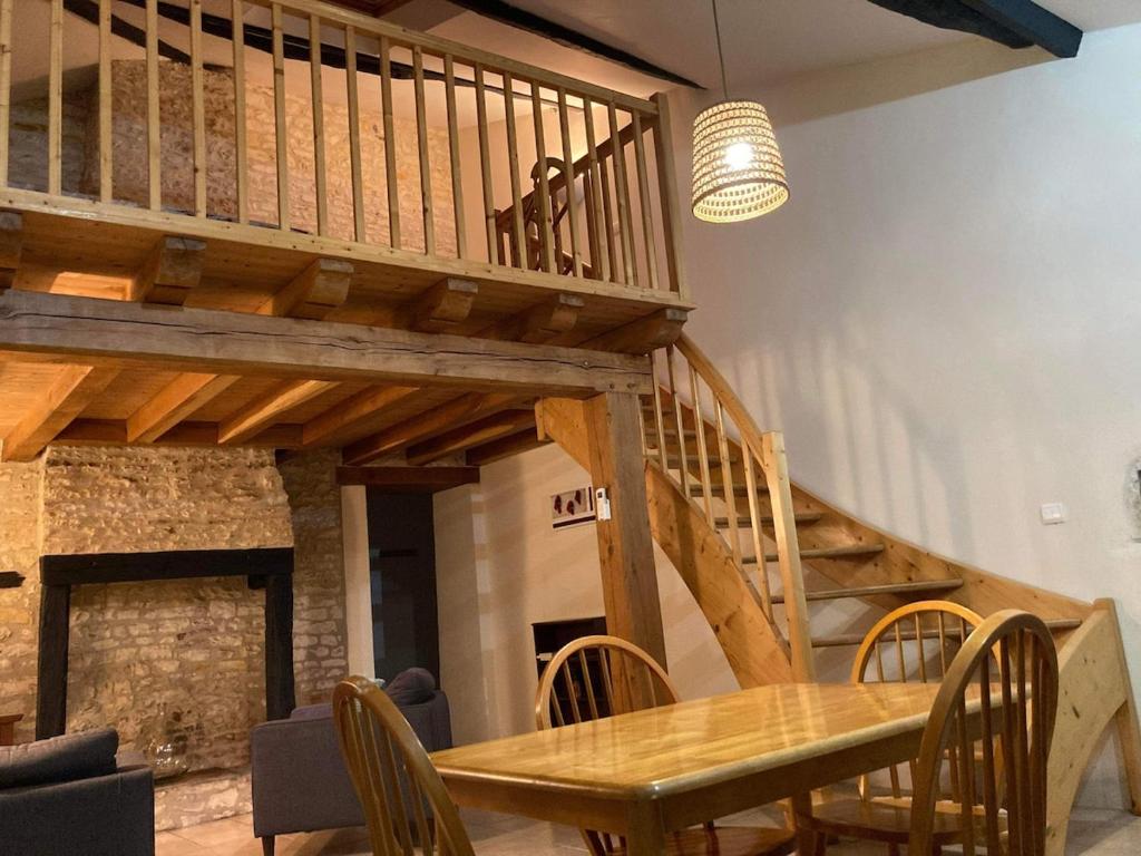 a dining room with a wooden table and a staircase at La maisonnette de la venelle in Chaunay