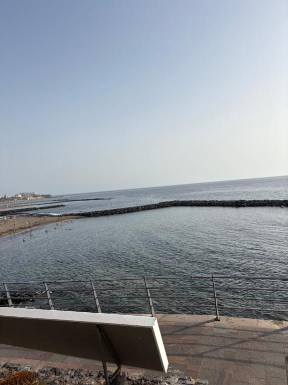 a view of the ocean from a beach with a bench at Hidden treasure in Playa de las Americas