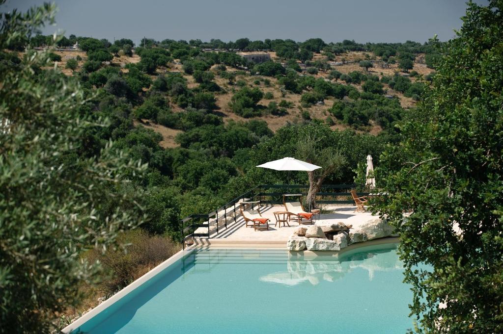 a swimming pool with an umbrella and a view of a valley at Le dimore di Cavalonga in Ragusa