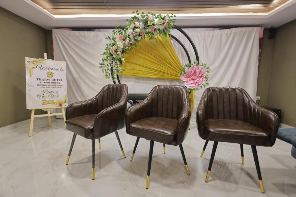 a table with three chairs and a flower arrangement at Tharvi Hotels in Jāmb