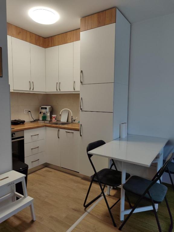 a kitchen with white cabinets and a table and chairs at Apartman BIM 58 in Banja Koviljača