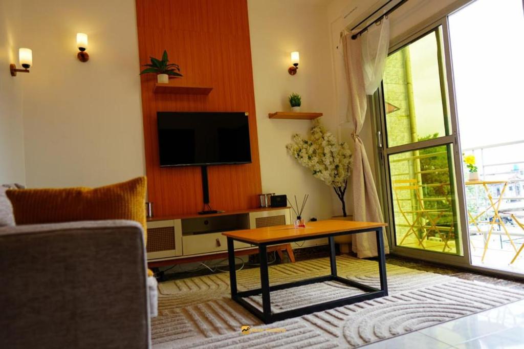 a living room with a tv and a coffee table at Cozy loft Bonamoussadi Douala in Douala