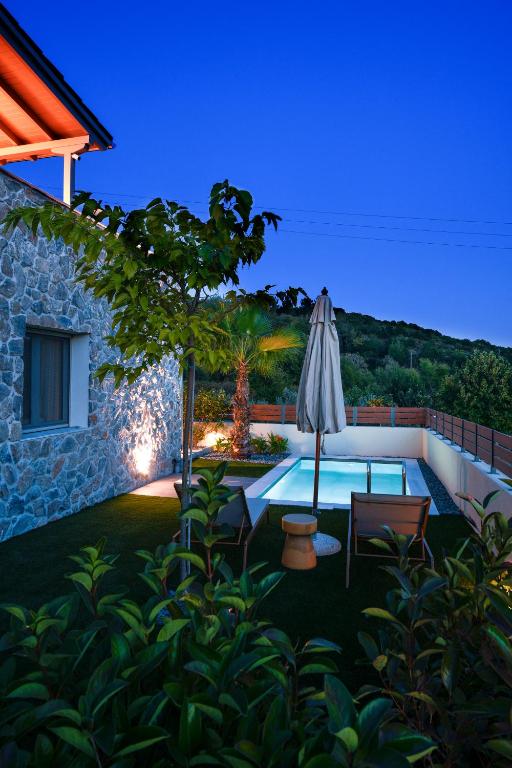 a backyard with an umbrella and a swimming pool at Golden Gaia Villas in Kipía