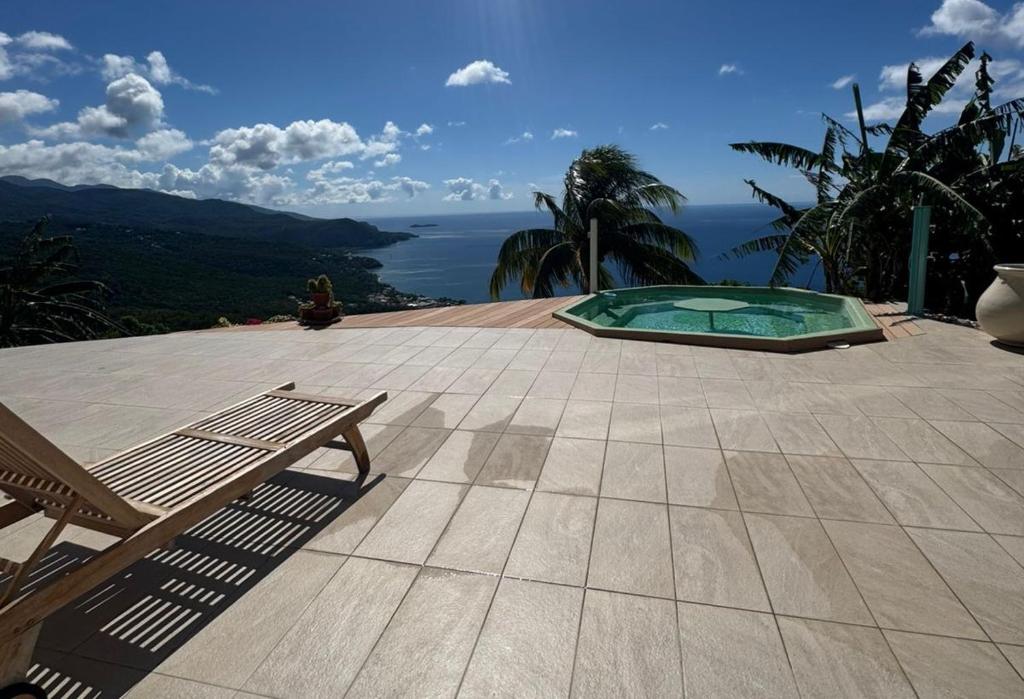 a patio with a bench and a view of the ocean at Bas de Villa Tropical Soul in Pointe-Noire