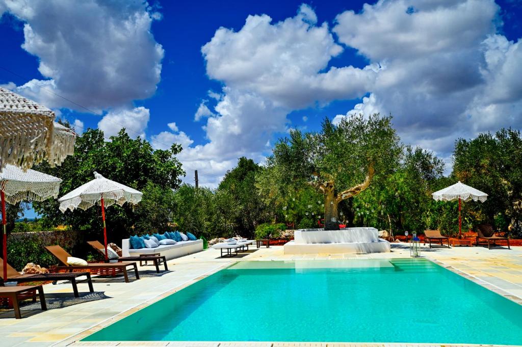 a swimming pool with chairs and umbrellas in a resort at Case Fra Gli Ulivi in Spongano