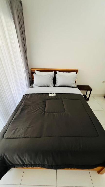 a bed with a black blanket on top of it at Ina Guesthouse in Lovina