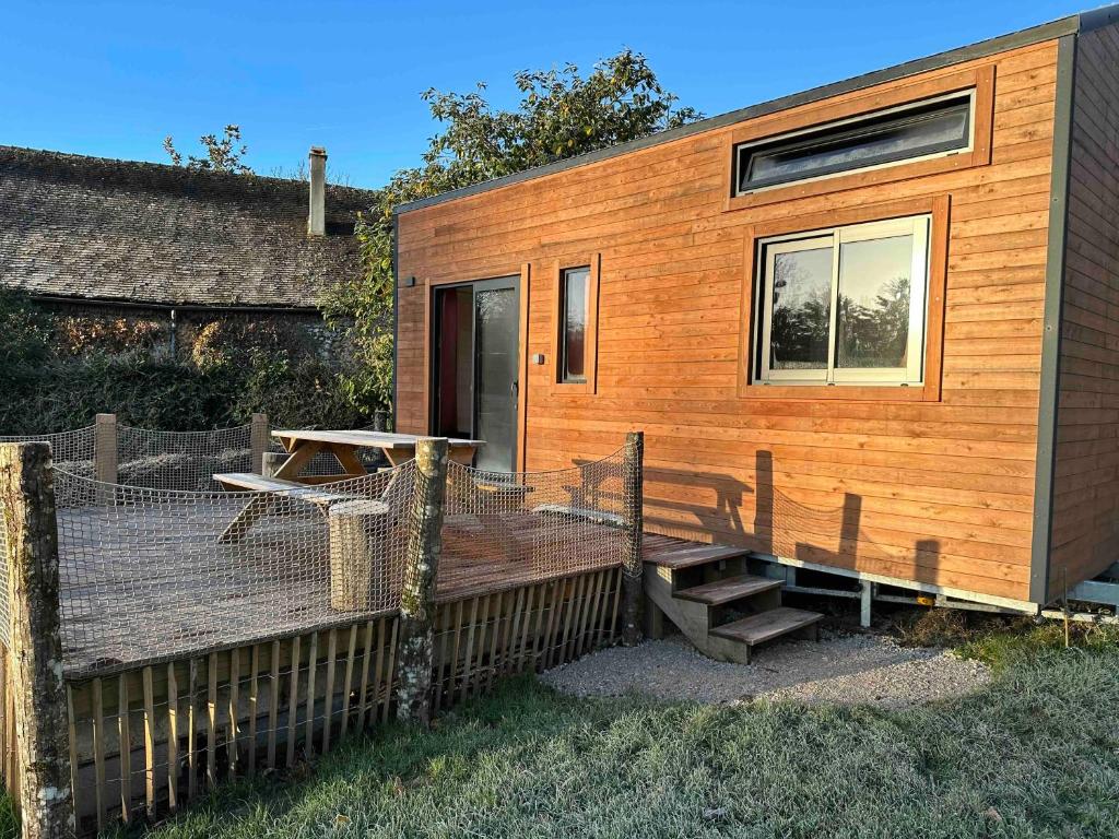 a tiny house with a deck and a table at Joy Tiny House Perche in Madeleine