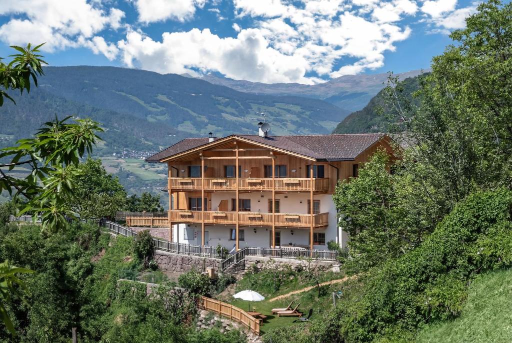 a house on a hill with mountains in the background at Gschlunerhof in Castelrotto